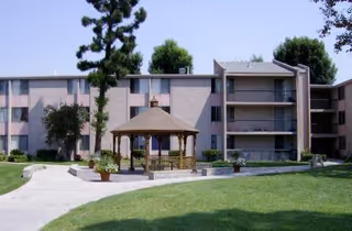 Exterior view of Del Amo Gardens with gazebo, lawn, and a multi-story building.