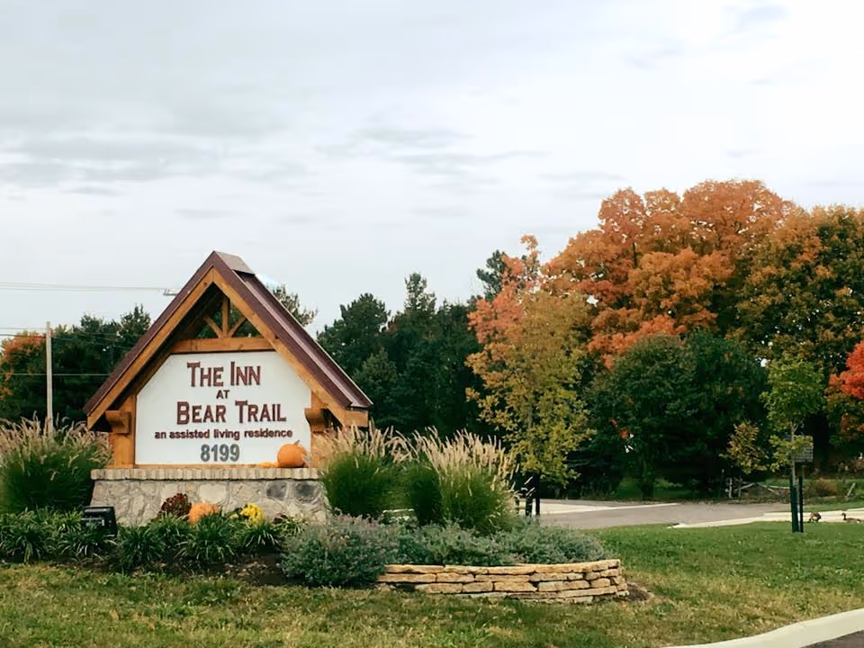 Entrance sign for The Inn at Bear Trail surrounded by landscaping and autumn-colored trees.