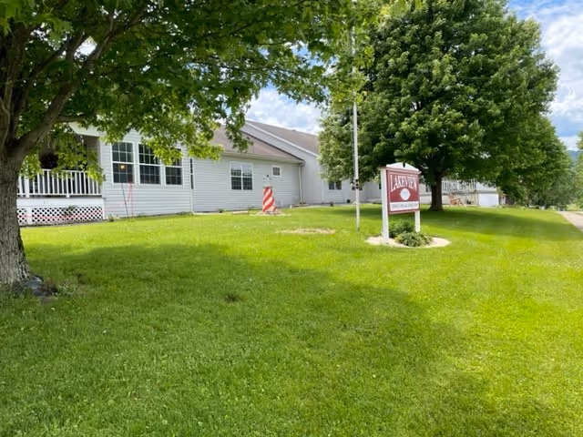 Exterior view of Lakeview Healthcare and Rehabilitation Center showing a white building with multiple windows, a green lawn, trees, and a red and white sign with the facility's name.