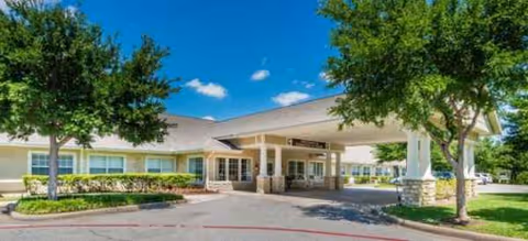 Exterior view of Brookdale White Rock facility entrance with trees and a covered drop-off area.