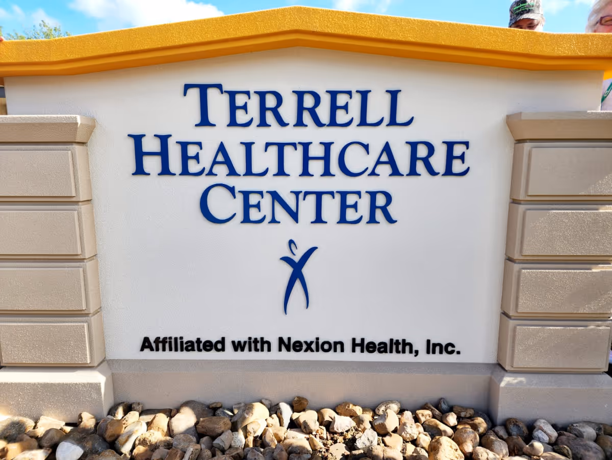 Outdoor sign for Terrell Healthcare Center with the text 'Affiliated with Nexion Health, Inc.' below it, surrounded by decorative stone pillars and rocks at the base.