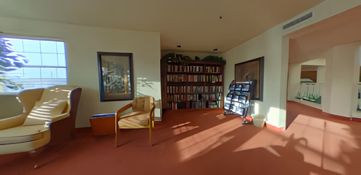 Sunlit common room with armchairs, a bookshelf, and a window casting shadows on red carpet.