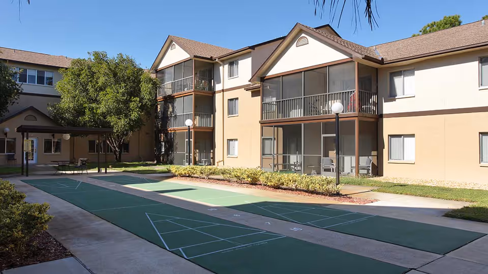 Exterior view of the Vitality Living Hudson building, featuring a courtyard with shuffleboard courts and balconies.
