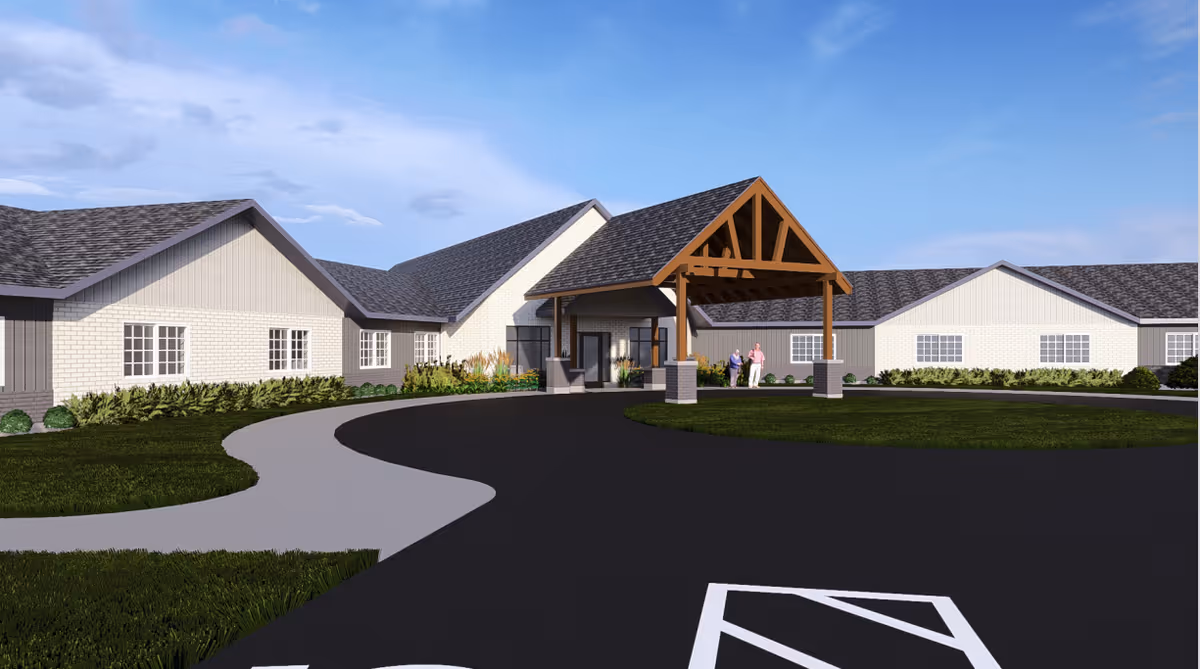 Front exterior of a single-story senior living building with a covered wooden porte-cochere, circular driveway, and landscaping.
