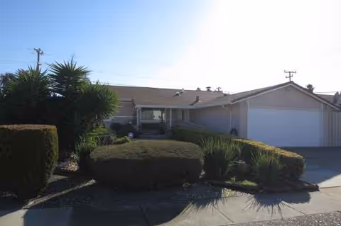 Single-story facility exterior with manicured shrubs and a two-car garage.