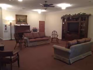 Cozy living room in a senior facility with sofas, chairs, and a TV cabinet.