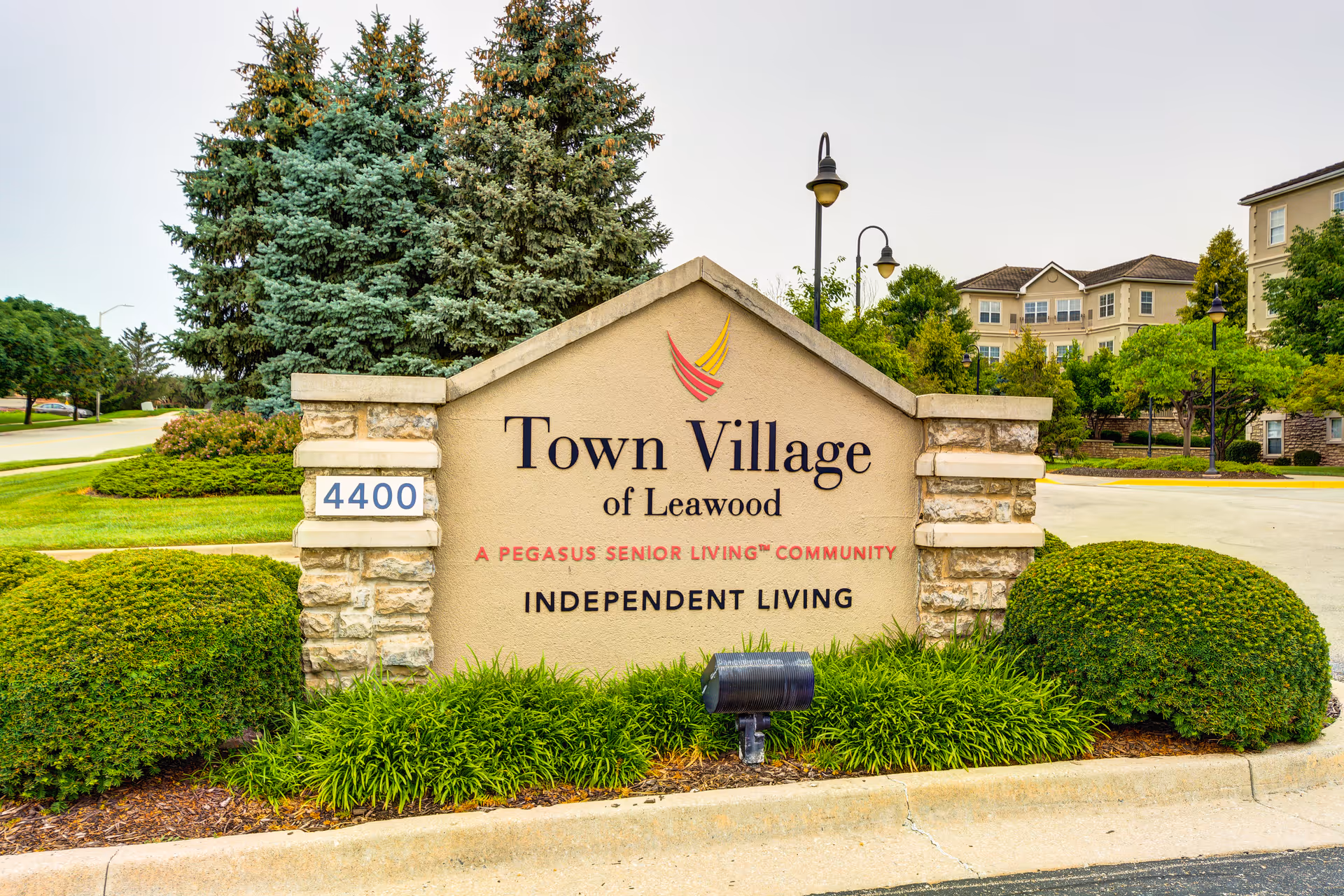 Entrance sign for Town Village of Leawood with landscaping and the apartment complex visible behind it.