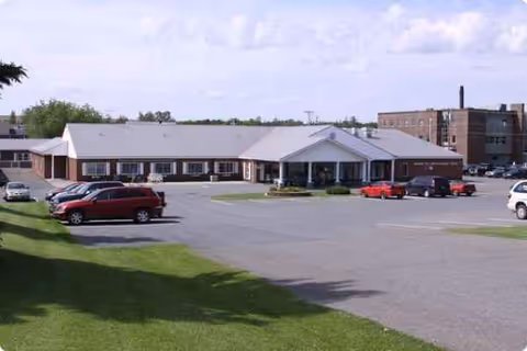 Single-story nursing facility with a parking lot in front.