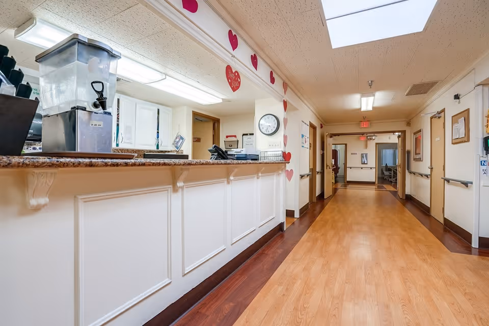 Reception desk and long hallway inside a senior living facility with heart decorations on the wall.