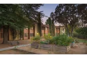 Exterior view of Sierra Sunrise Apartments building with brick walls, trees, and raised garden planters.