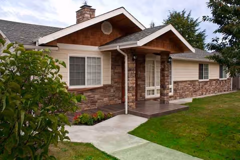 Single-story home exterior with stone veneer, front porch, and landscaped lawn.