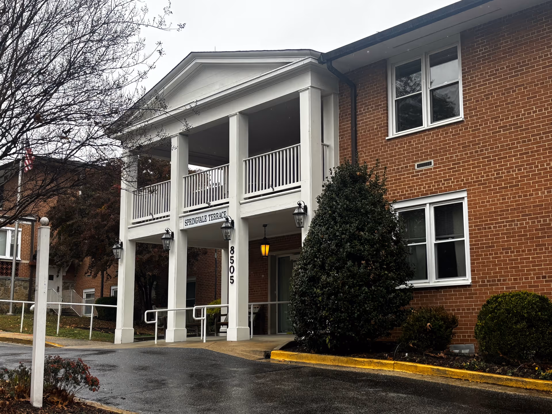 Front entrance of a two-story brick building with white columns, a balcony and a sign reading "Springvale Terrace".
