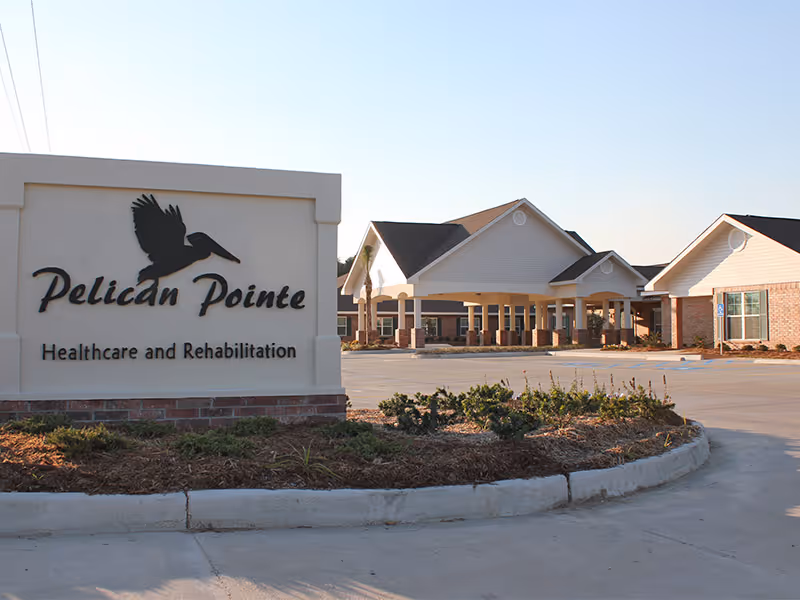 Front entrance of Pelican Pointe Healthcare and Rehabilitation with a large stone sign and drive-up canopy.