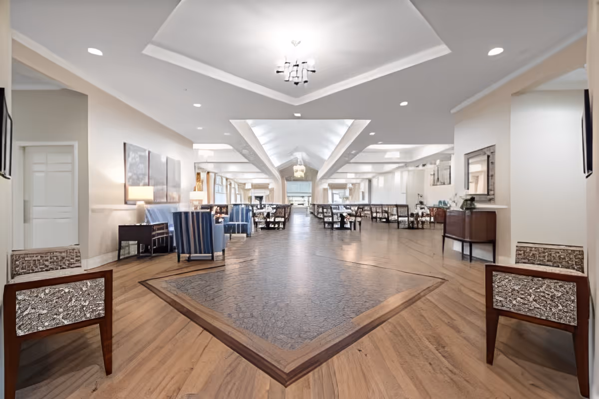 Spacious, well-lit common area with lounge seating and dining tables under a vaulted ceiling.