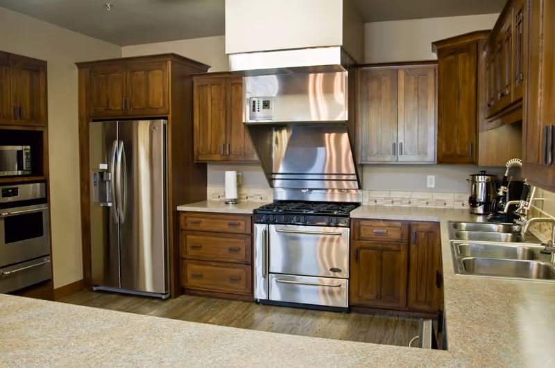 Modern kitchen with stainless-steel appliances, wooden cabinets, and a double sink.