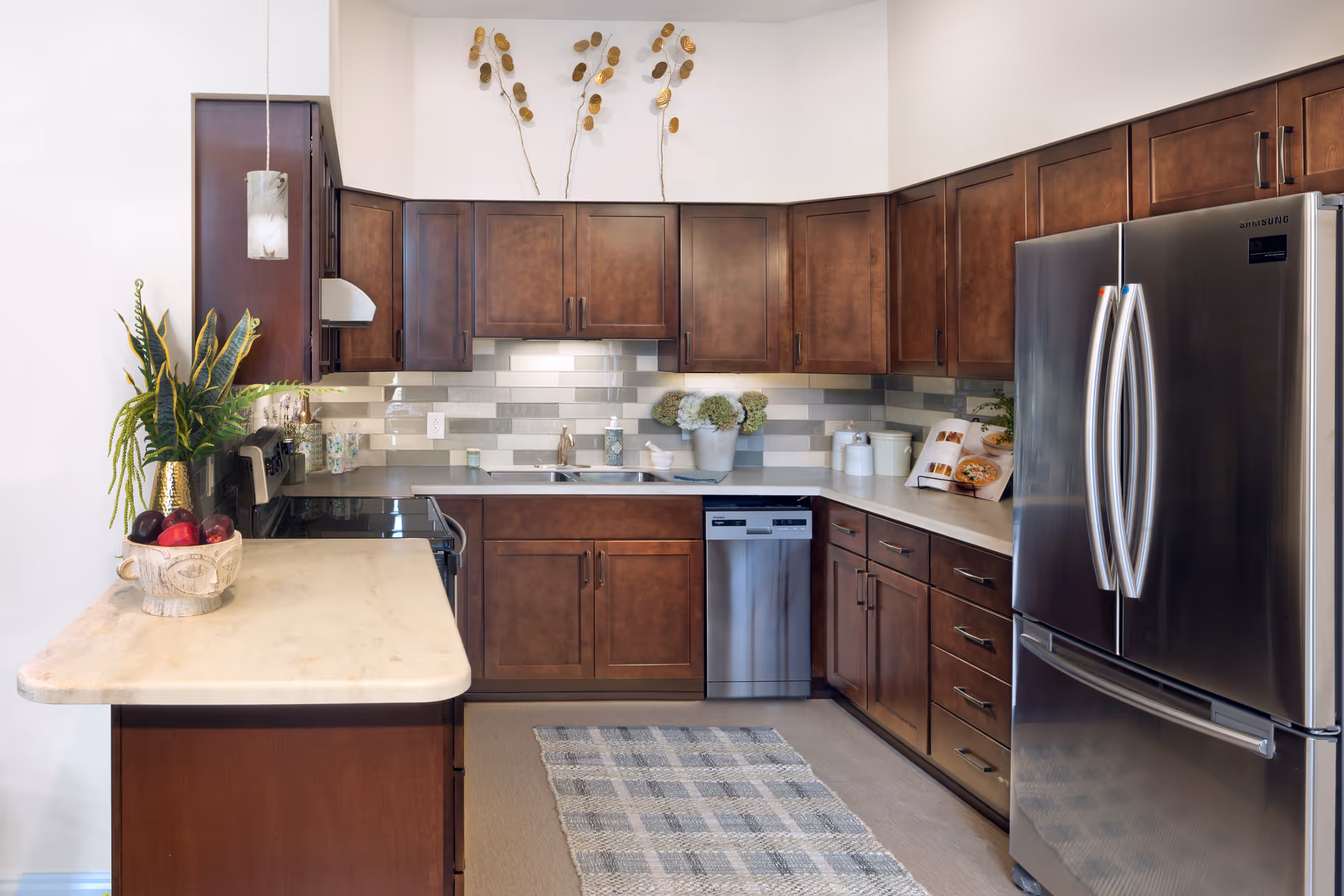 Bright modern kitchen with dark wood cabinets, stainless steel French-door refrigerator and dishwasher, and a light countertop island.