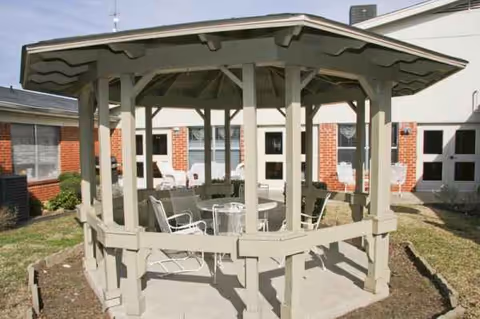 Wood gazebo with metal chairs and tables in a courtyard outside The Laurenwood Nursing and Rehabilitation.