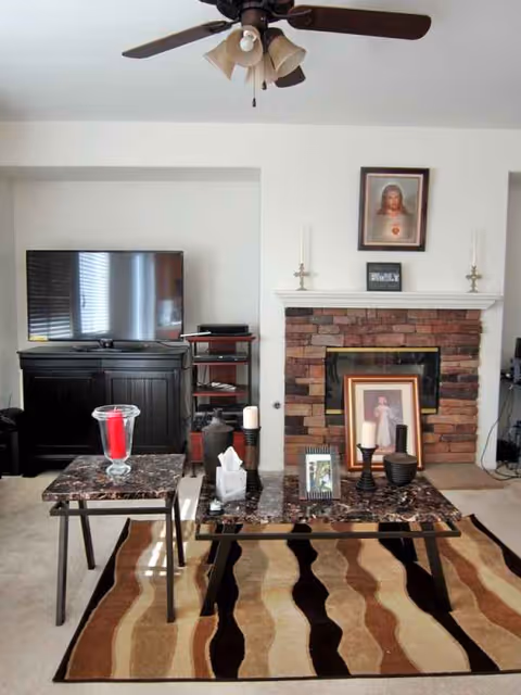 Living room with a TV, fireplace, coffee tables, and framed photos.