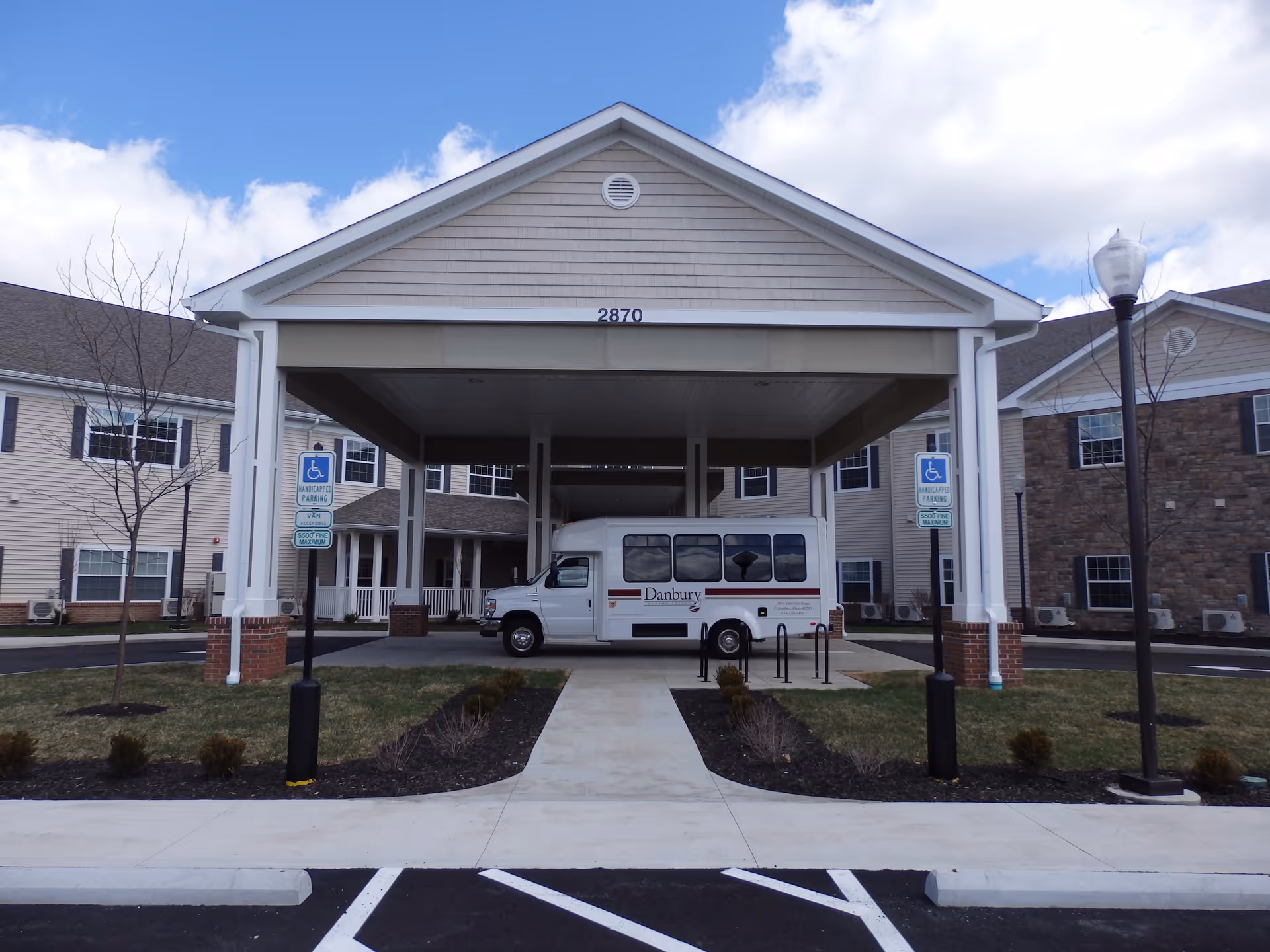 Exterior view of Danbury Columbus facility with entrance porte-cochere and bus.