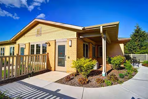 A single-story brick and beige siding facility exterior with a covered entry and landscaping.