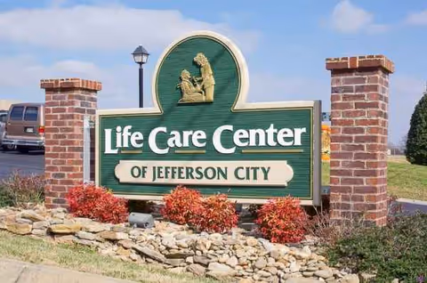 Entrance sign reading Life Care Center of Jefferson City, brick pillars and landscaped rocks.