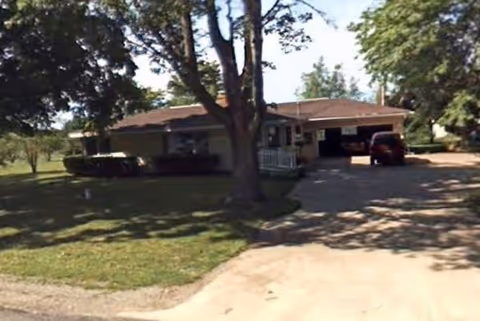 Single-story senior care home with a driveway, front yard, and carport.