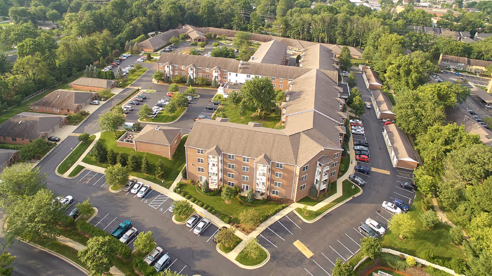 Aerial view of Bell Trace senior living complex with parking and trees.
