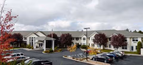 Exterior view of Klamath Falls Senior Living building with parking lot and autumn trees.