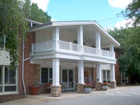 Two-story brick building with white columns and a spacious front porch.