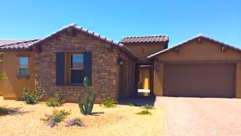 Front view of a single-story stone-assisted living facility with a two-car garage.
