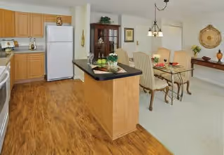 Open-plan kitchen with a center island, white appliances, and an adjacent dining table with chairs.