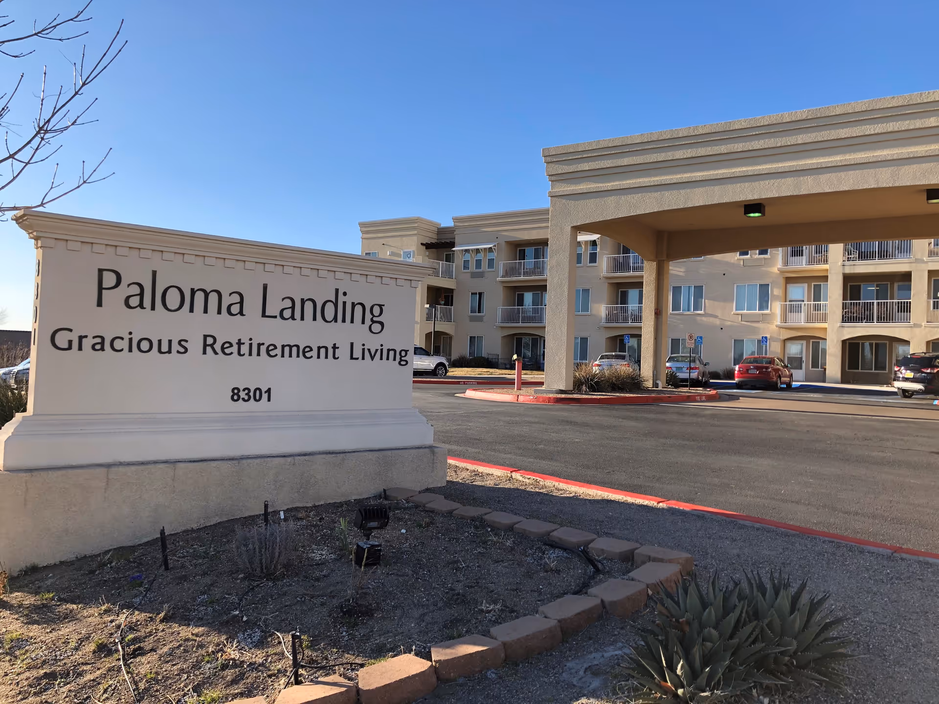 Exterior view of Paloma Landing retirement community with large sign and parking lot