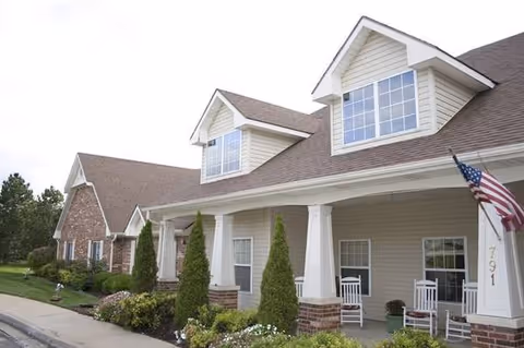 Front exterior of Homestead Assisted Living of Olathe South with porch chairs and flag