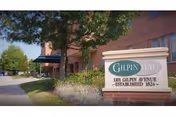 Exterior view of Gilpin Hall building with a sign in the foreground that reads 'Gilpin Hall, 1101 Gilpin Avenue, Established 1824'. The building is partially visible with trees and landscaping along the sidewalk.