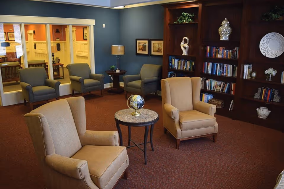 Cozy common lounge with armchairs, a small round table topped by a globe, and a built-in bookshelf.