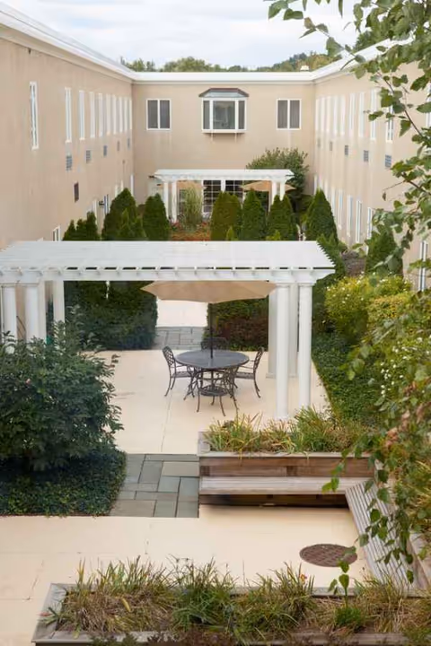 Outdoor courtyard at Pioneer Valley Health & Rehabilitation with seating under a white pergola.