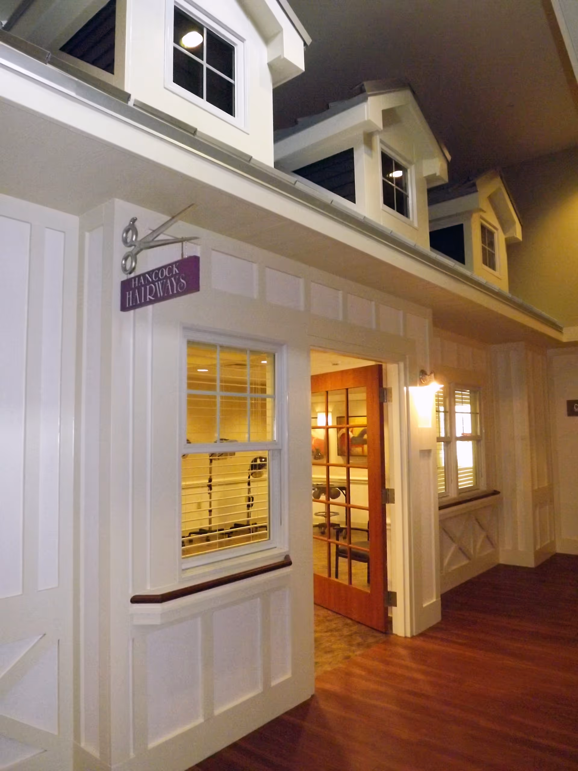Interior corridor showing a mock storefront hair salon entrance with a sign reading "Hancock Hairways" and small dormer windows above.