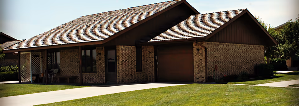 Single-story brick ranch-style building with an attached garage, covered porch, and a manicured lawn.