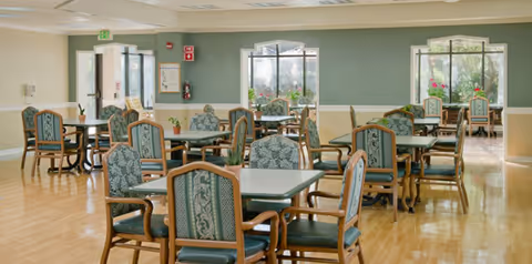 Spacious dining room with multiple tables and cushioned chairs.