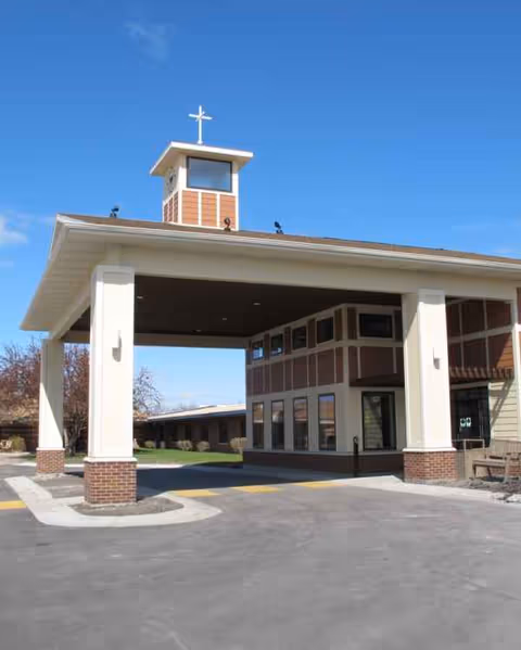 Exterior view of Fargo Elim Health Care Center entrance with a covered drive and cross.
