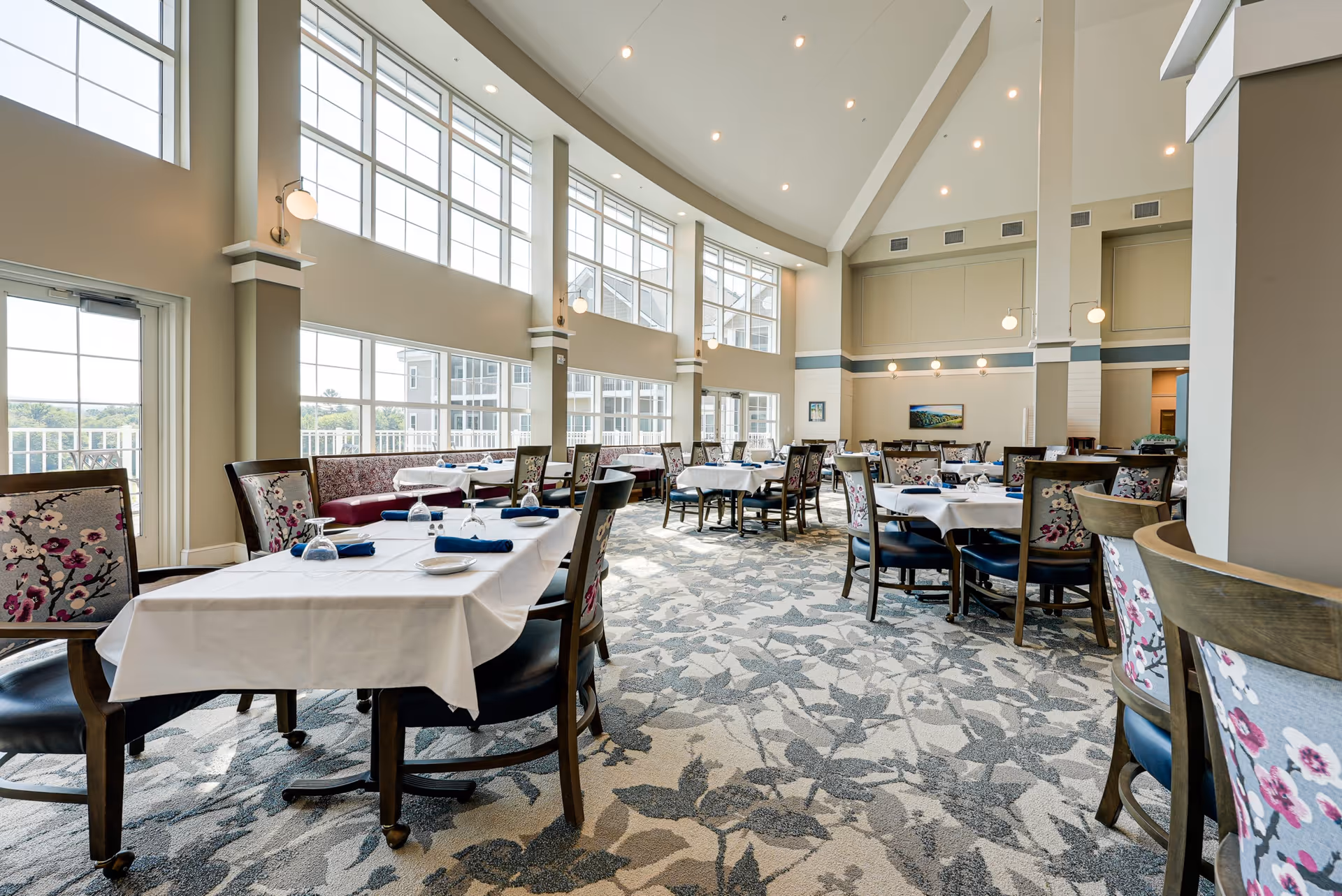 Bright, spacious dining room with set tables, high ceilings and large windows.