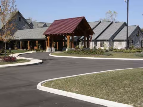 Exterior view of a senior living facility with a curved driveway and covered entrance.