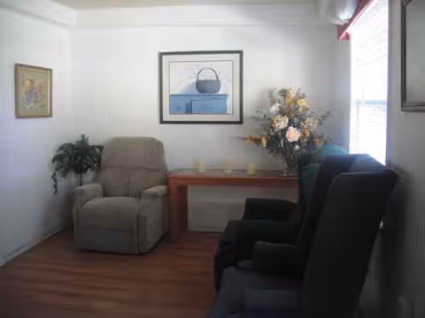 A cozy living room with two recliners, a wooden table, wall art, and a floral bouquet.