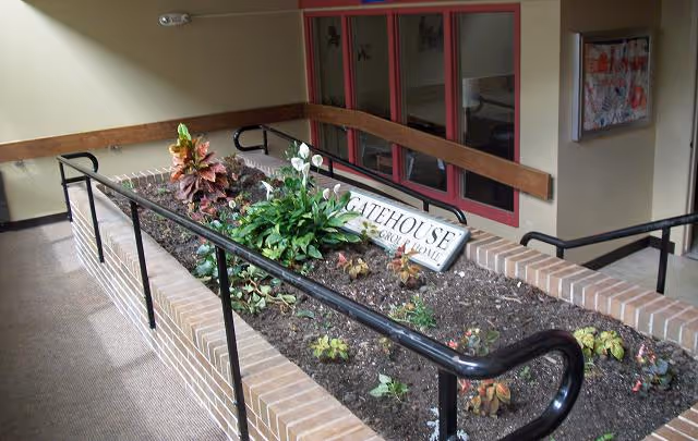 Entrance to GateHouse Senior Living with brick planter, railing, and accessible ramp.