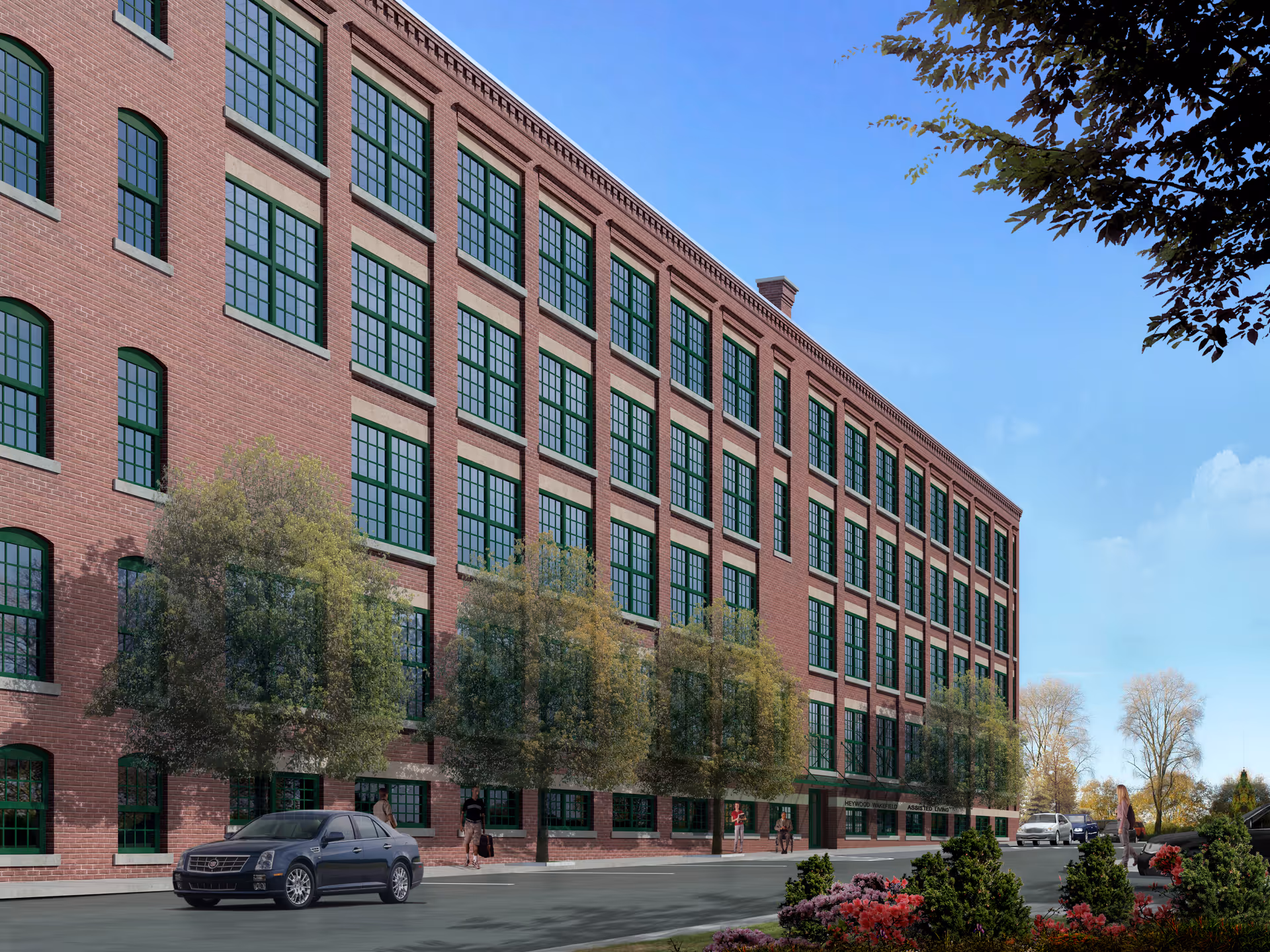 Brick five-story building with rows of green-framed windows along a tree-lined street with parked cars and pedestrians.