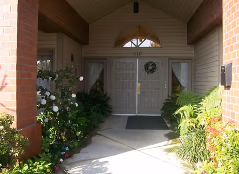 Covered entrance to the Summerfield of Roseville building with double doors, a wreath, and plants lining the walkway.