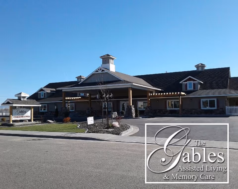 Front exterior of The Gables Assisted Living building with a covered entrance, driveway, and landscaped circular drive.