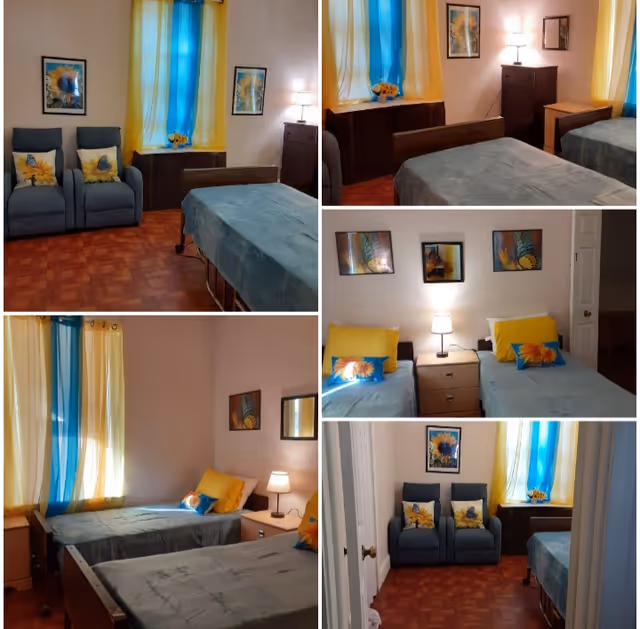 Collage of images showing a bedroom with two single beds covered in blue bedspreads and yellow pillows. The room features blue and yellow curtains, framed artwork on the walls, a wooden floor, bedside tables with lamps, a chest of drawers, and two blue armchairs with decorative cushions.