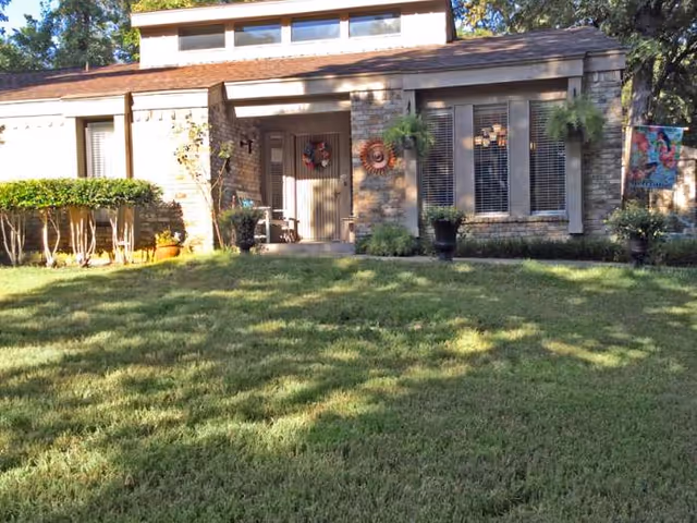 Front view of a brick-assisted living facility with wreaths, windows, and a large lawn.
