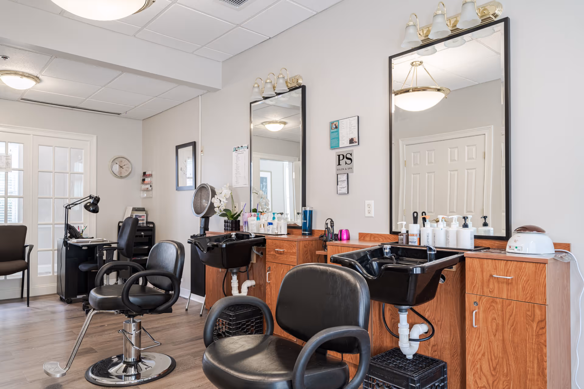 Interior hair salon with styling chairs, shampoo sinks, large mirrors, and wooden cabinets.